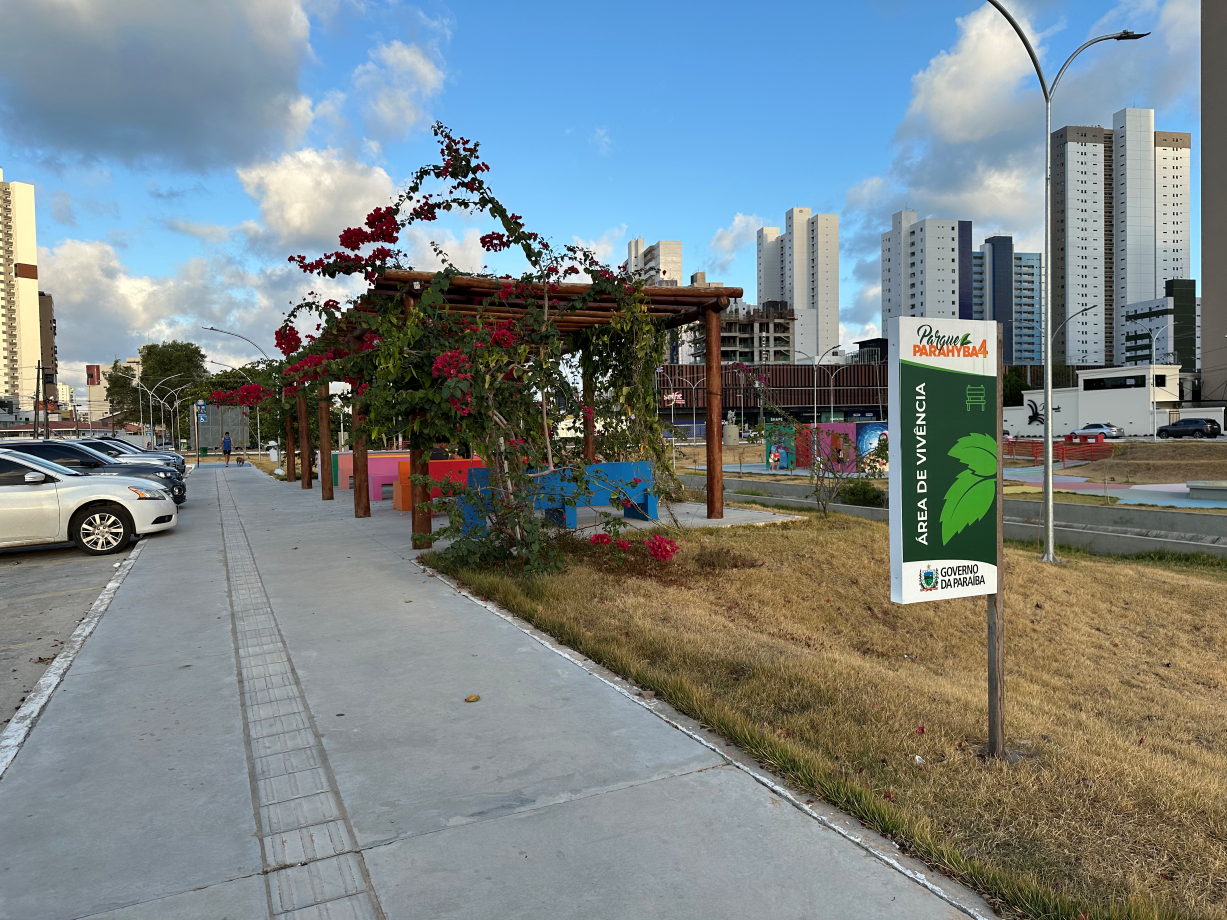 Área de vivência do Parque Parahyba IV, cercada por vegetação e prédios ao fundo